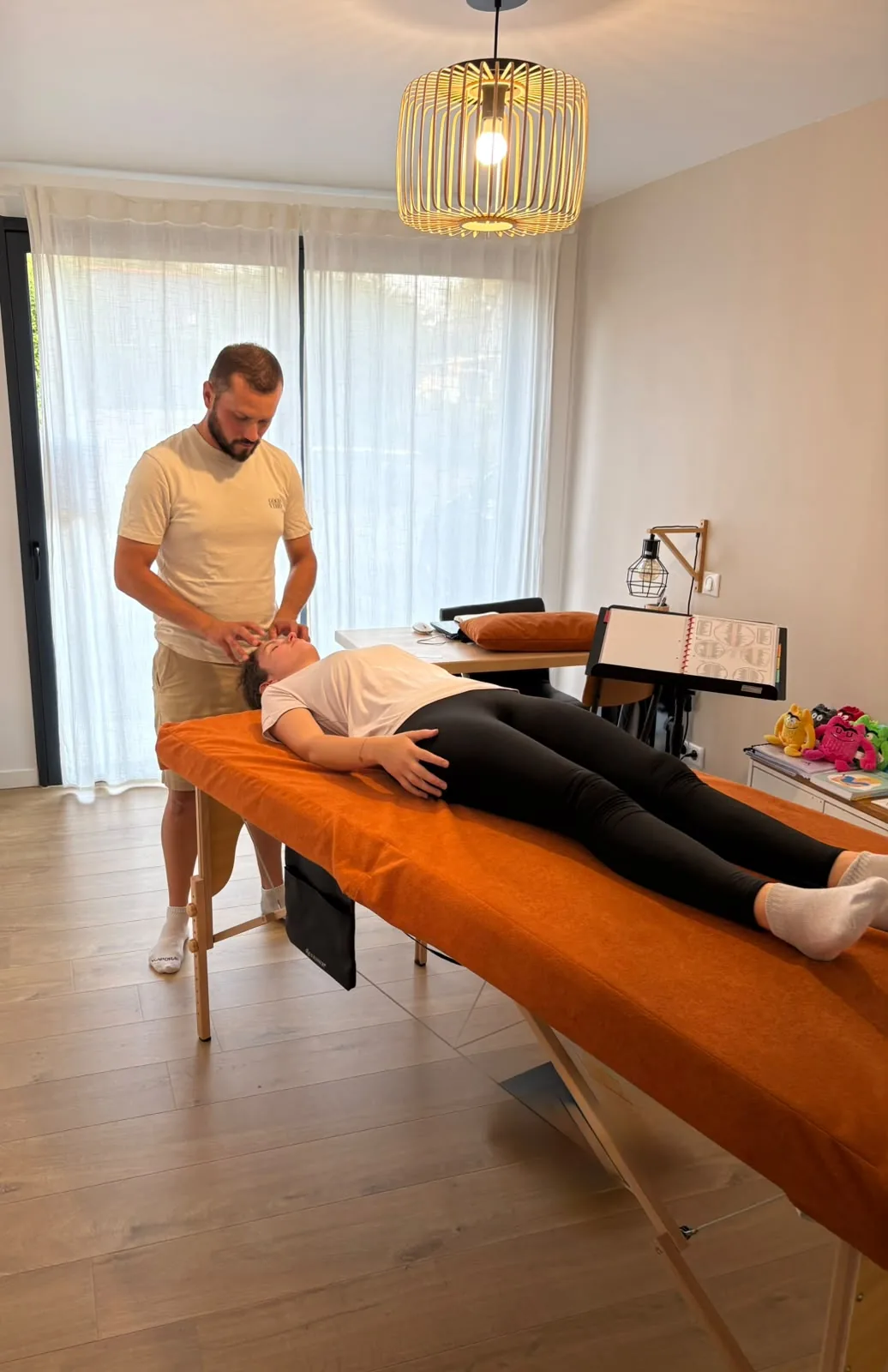 Séance de kinésiologie : le praticien accompagne une personne allongée sur la table.